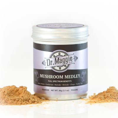 Dr. Maggie Mushroom Medley powder jar with purple and black label beside small piles of tan mushroom powder. Text includes product name and net weight of 88g (3.1 oz).