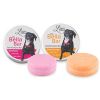 Two Bella Bar pet shampoo bars shown with their matching tins. The strawberry bar and tin appear on the left in pink, and the sweet orange bar and tin appear on the right in orange. Each tin features a black dog on the label, with the solid shampoo bars placed in front.